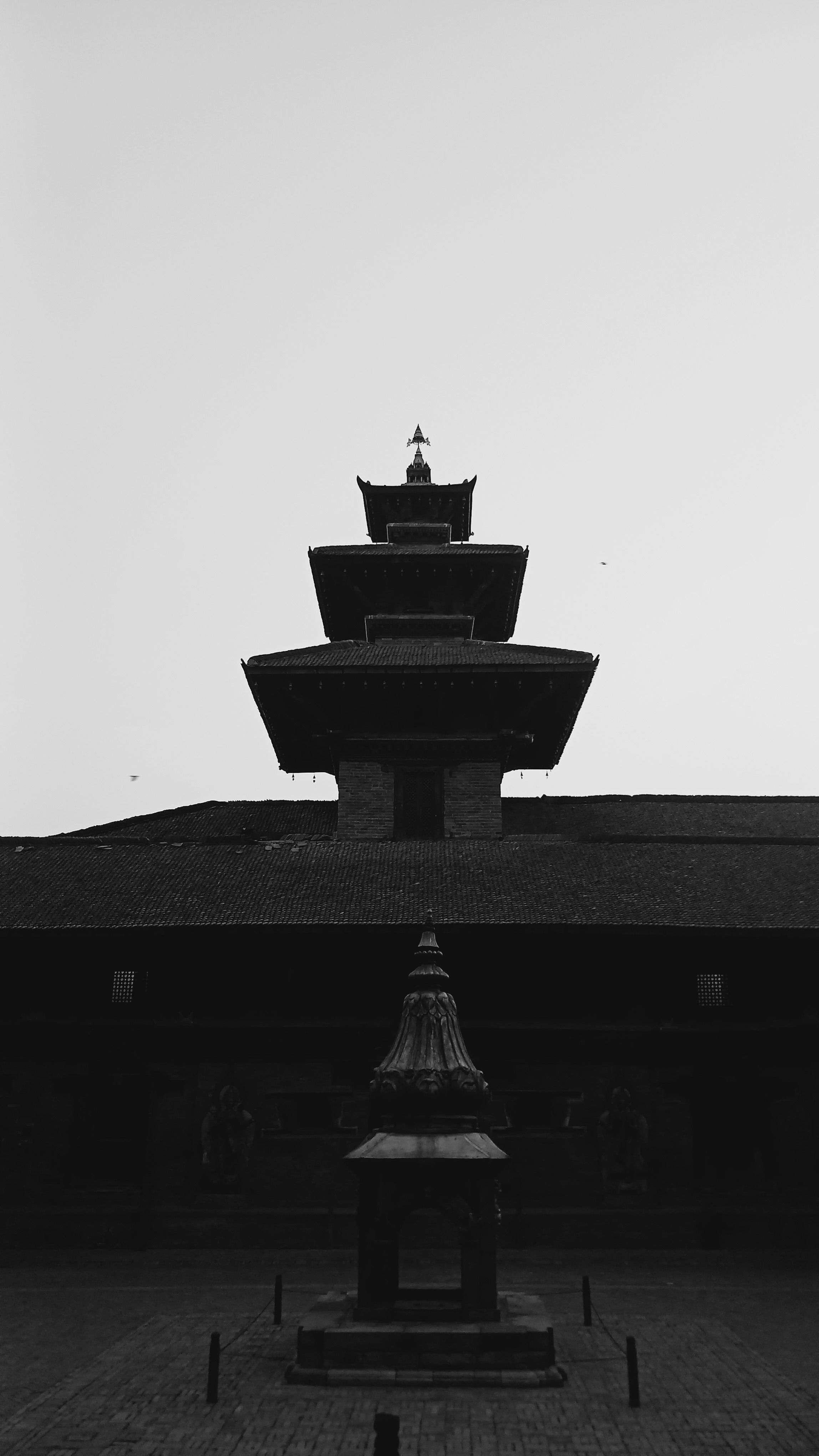A dramatic black and white silhouette of an ancient multi-tiered pagoda tower at twilight.