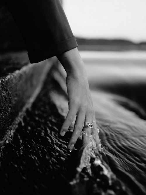 Free A woman's hand delicately touches flowing water, capturing tranquility and reflection in black and white. Stock Photo