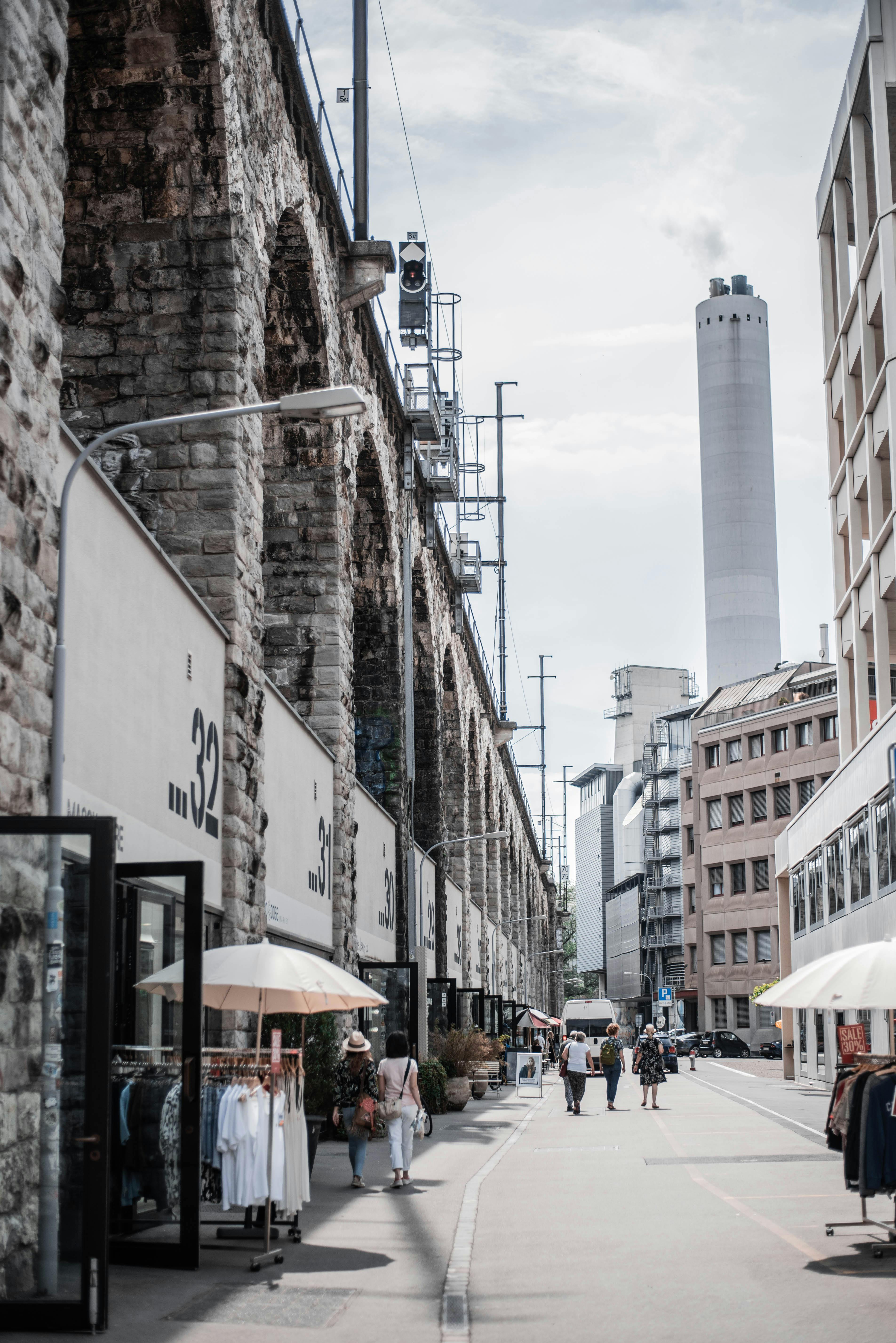 晴朗的天空下，繁华的城市街道上，商店、行人和石质建筑构成了它的特色