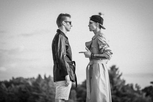 Grayscale Photo of Man and Woman Standing Near Trees