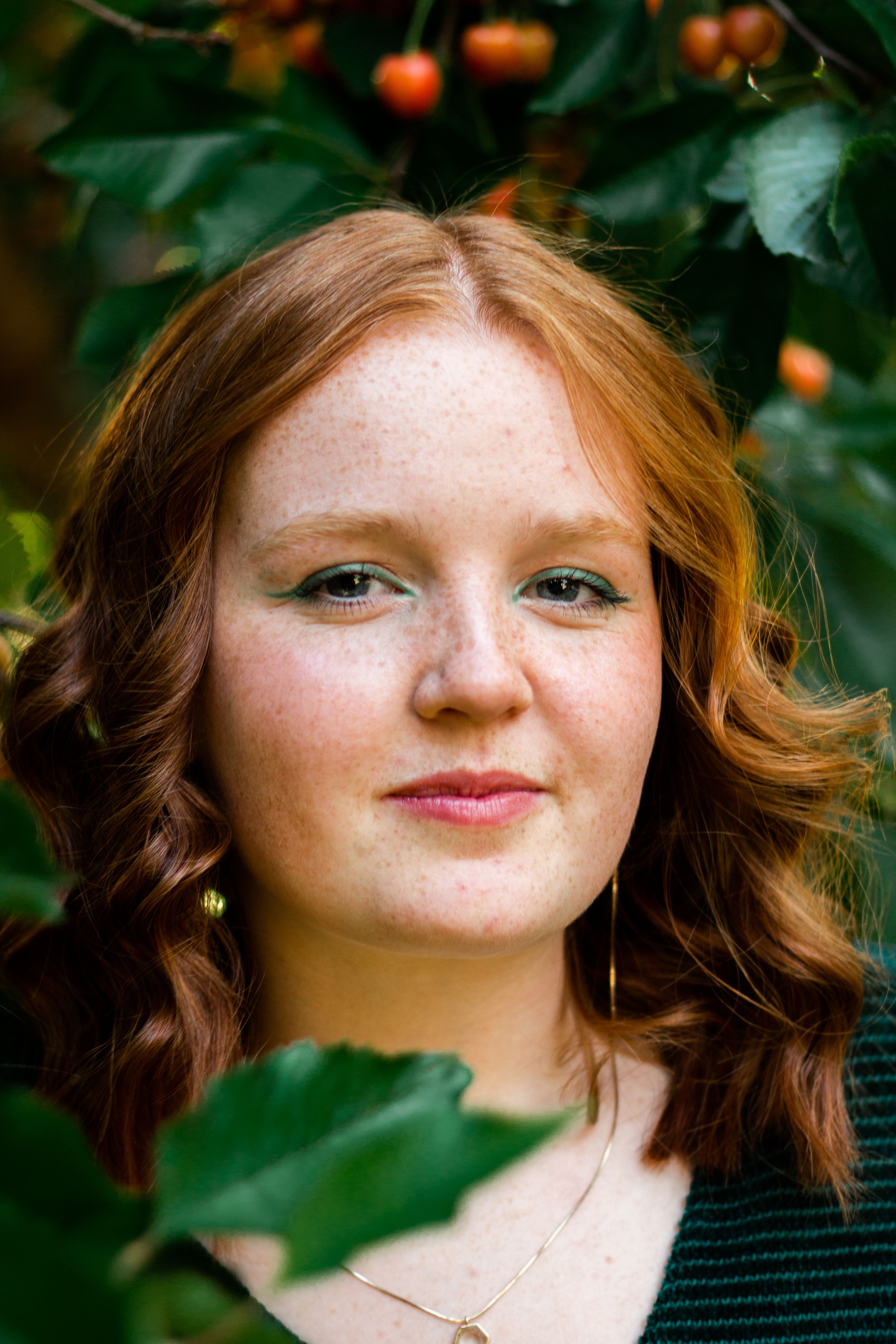 A captivating portrait of a freckled redhaired woman among green foliage, showcasing natural beauty.