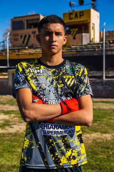 Teen soccer player poses confidently in a vibrant team jersey on a sunny day.