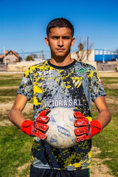 Teen soccer player outdoors holding a ball in summer sports gear.