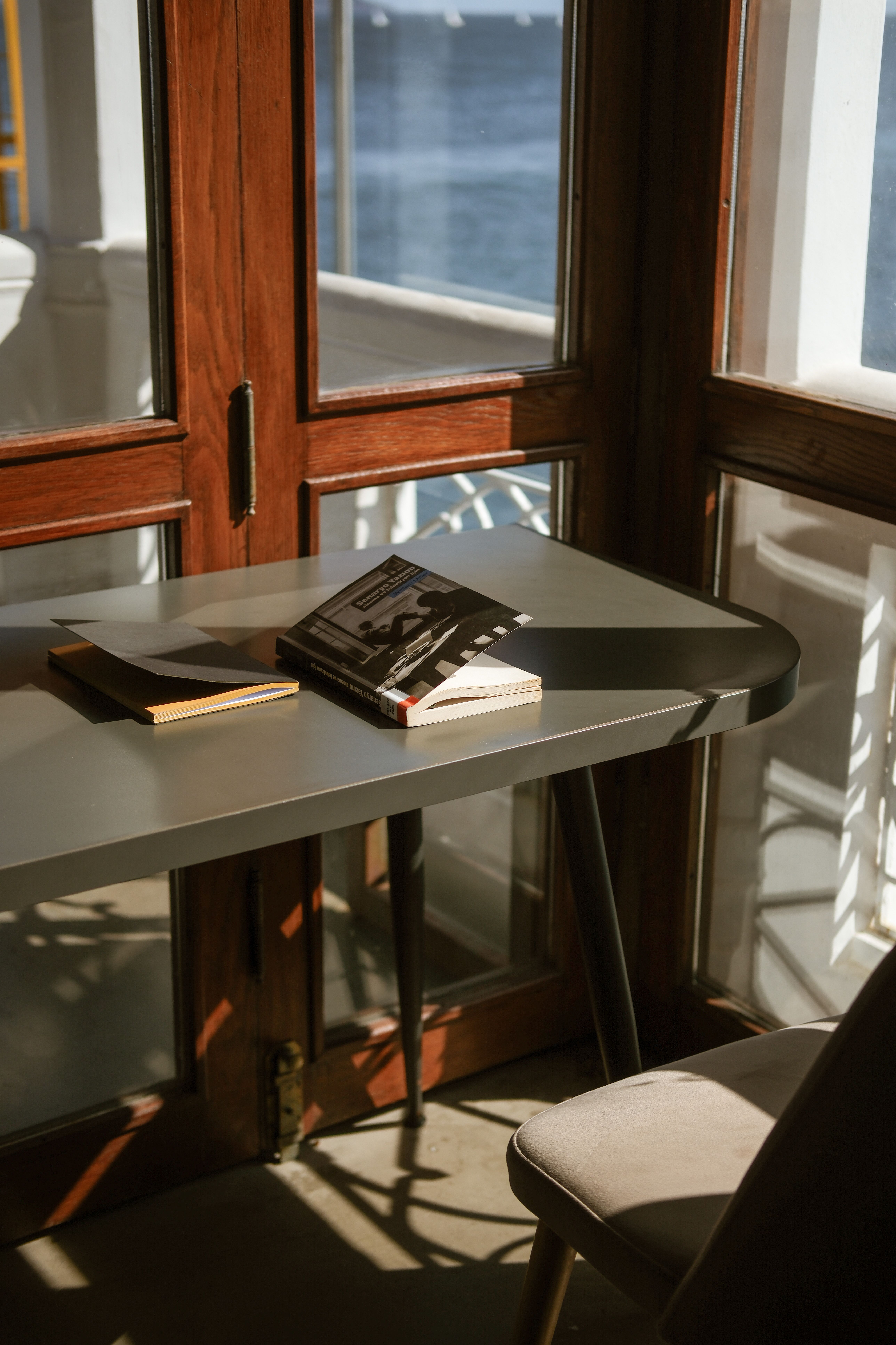 A desk with a book and a chair by the window · Free Stock Photo