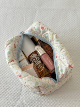 Elegant makeup bag with luxury skincare items on a textured surface, perfect for travel.