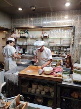 Two chefs skillfully preparing food in a bustling restaurant kitchen, surrounded by kitchenware.