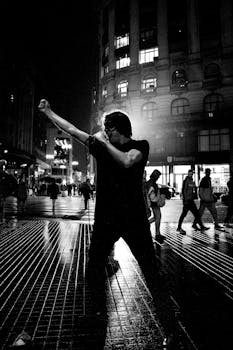 Black and white image of a street performer singing in Buenos Aires cityscape.