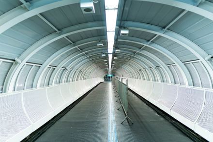 Symmetrical metal and glass tunnel walkway — photo by Wallace Chuck on Pexels
