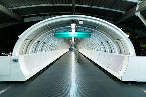 Free A modern pedestrian tunnel with an exit sign, featuring sleek architecture in a subway station. Stock Photo