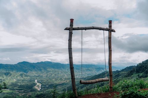 Free A tranquil scene featuring a rustic wooden swing set against a stunning mountain valley view, emphasizing nature's beauty. Stock Photo