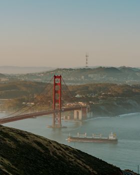 Stunning view of the Golden Gate Bridge and cargo ship during sunrise in San Francisco Bay.