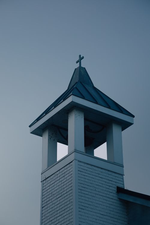 Free A traditional church tower with a cross against a clear blue sky, symbolizing faith and spirituality. Stock Photo