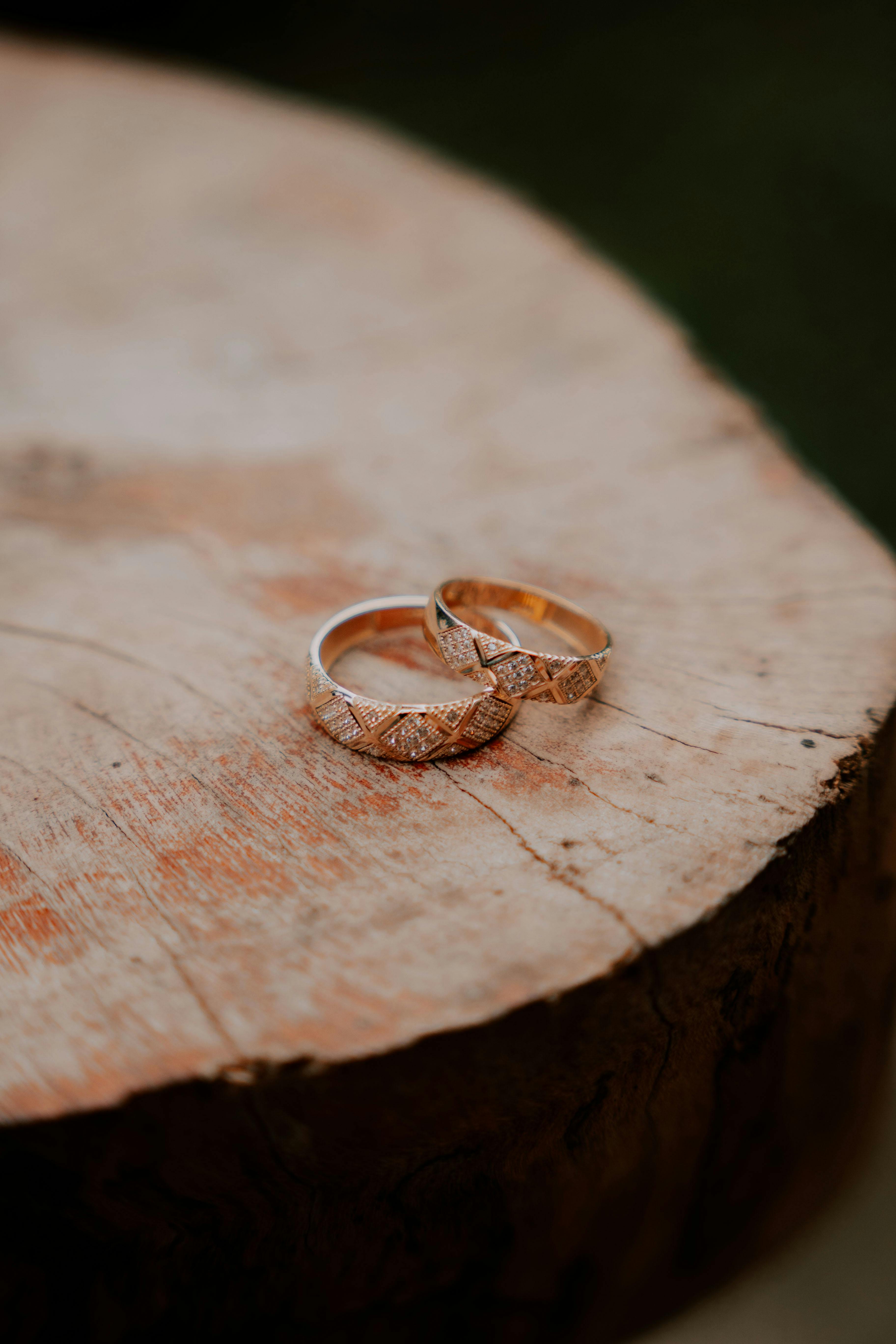 Close-up of two intricate wedding rings on a rustic wooden surface, symbolizing love and commitment.