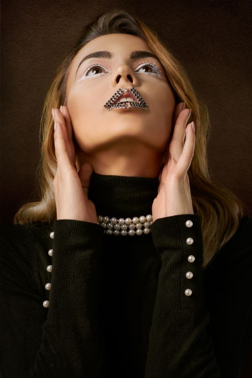 Free Striking portrait of a woman with pearl embellishments and artistic makeup wearing a stylish black outfit. Stock Photo