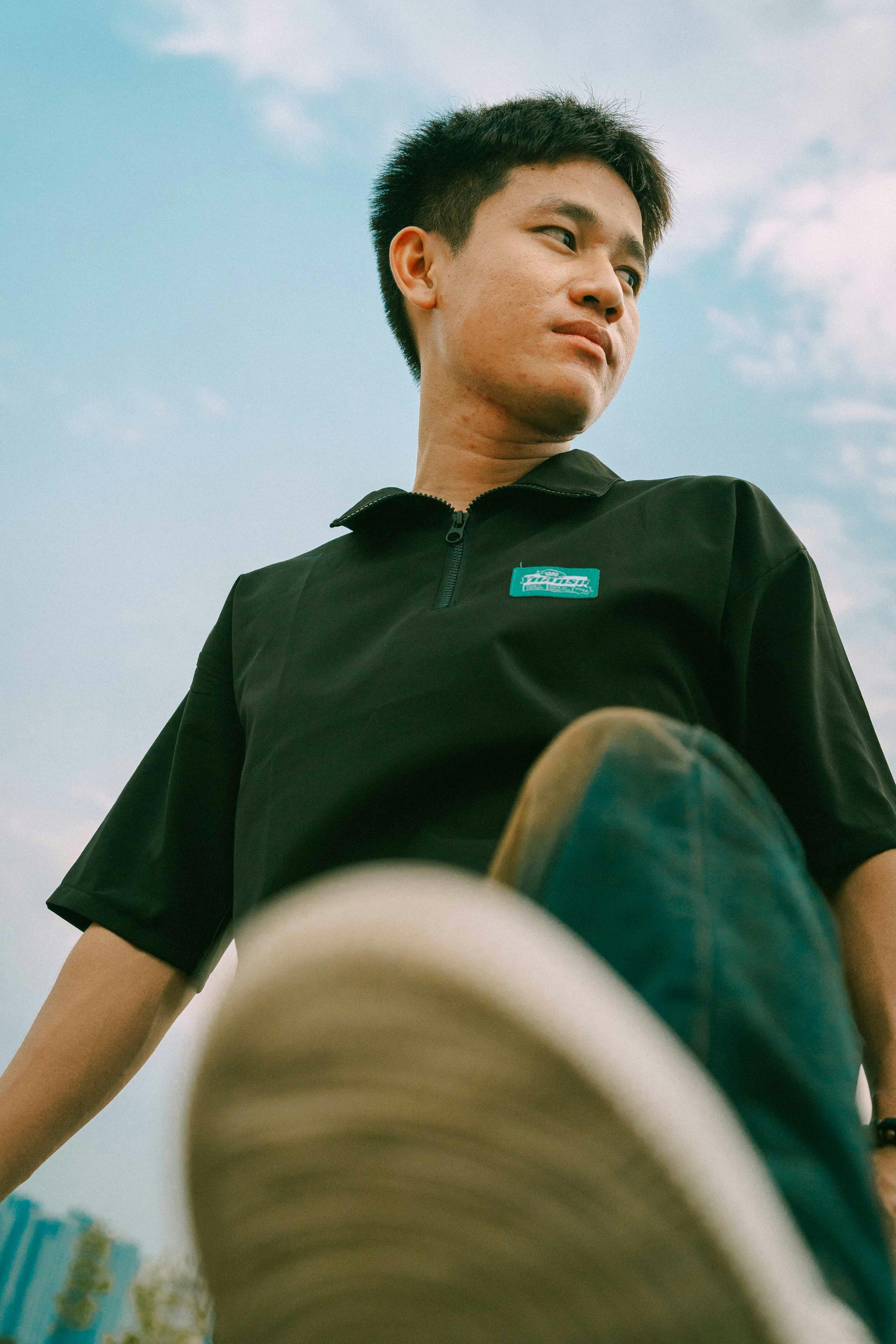 a young man in black shirt and jeans sitting on a skateboard