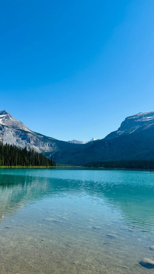 Free Breathtaking view of a turquoise lake surrounded by majestic mountains and a clear blue sky. Stock Photo