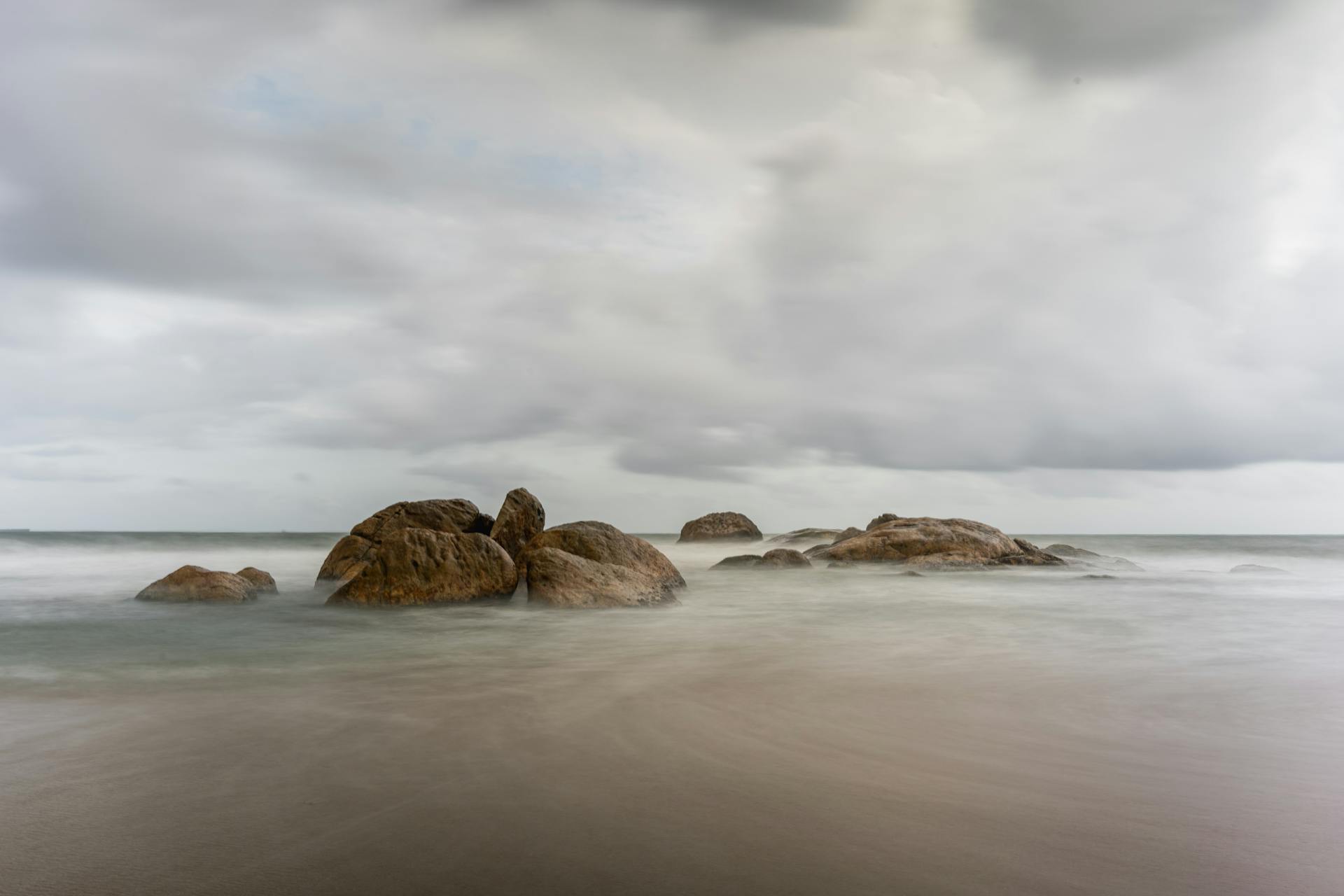 Tranquil scene of rocks at Galle Beach, Sri Lanka under an overcast sky.