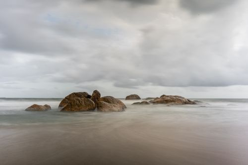 Free Tranquil scene of rocks at Galle Beach, Sri Lanka under an overcast sky. Stock Photo