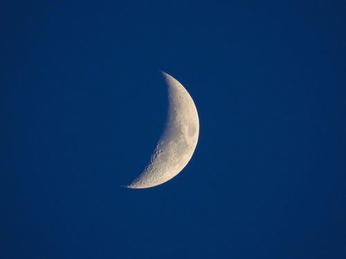 Free Stunning crescent moon against a deep blue night sky, showcasing lunar craters. Stock Photo