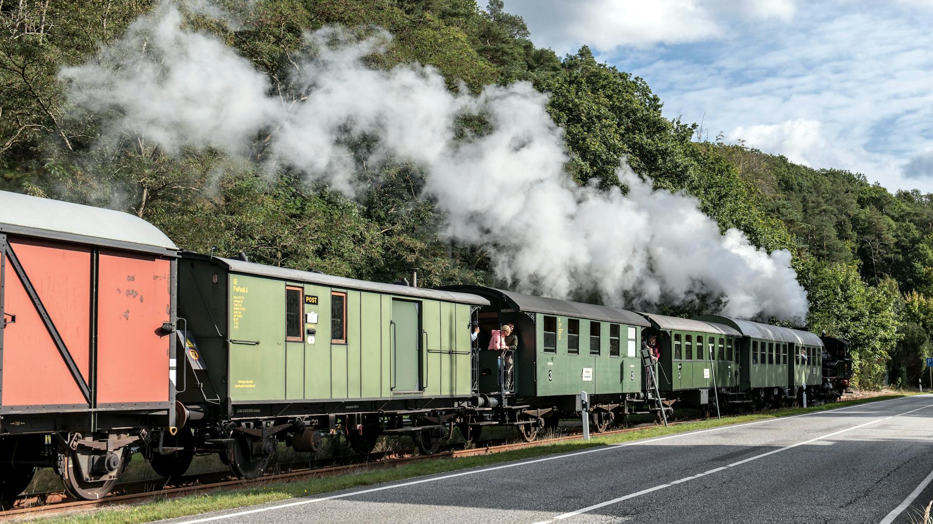 A historical steam train releasing smoke in Geesthacht, Germany, evoking nostalgia and industrial charm.