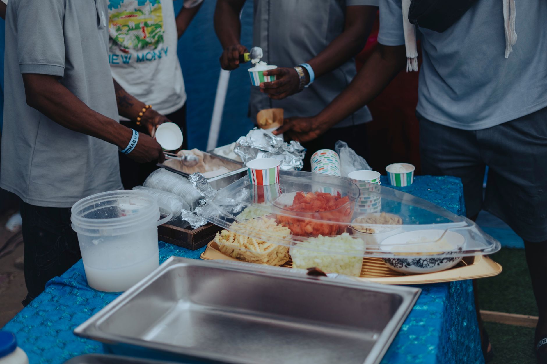 Group of adults preparing food at an outdoor event with diverse snacks displayed.