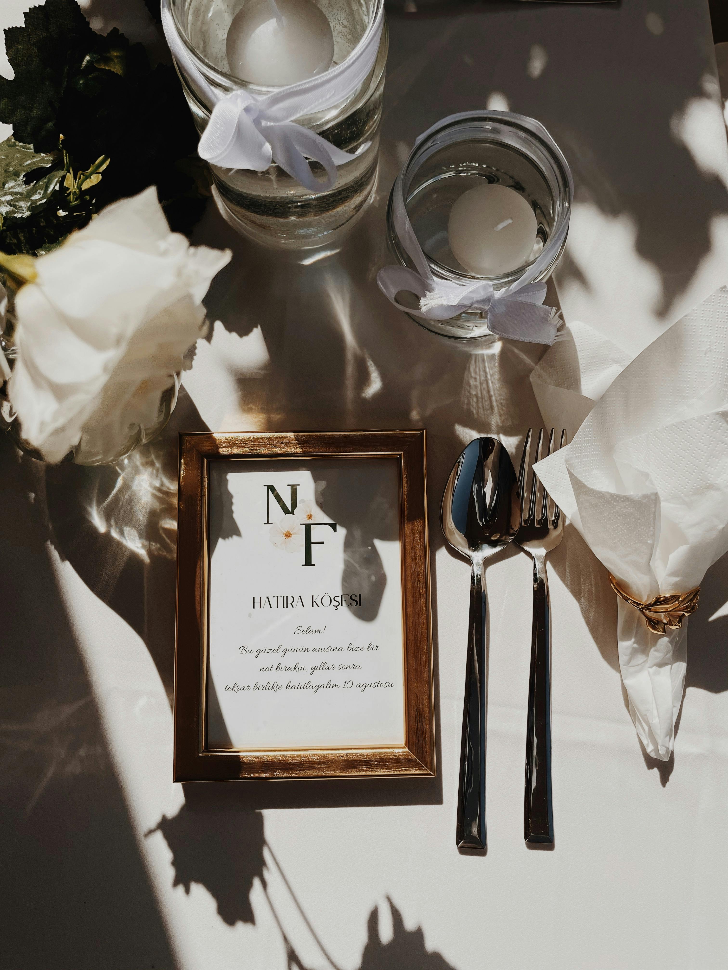 Charming flat lay of a wedding table setting, featuring candles, floral decor, and elegant cutlery.