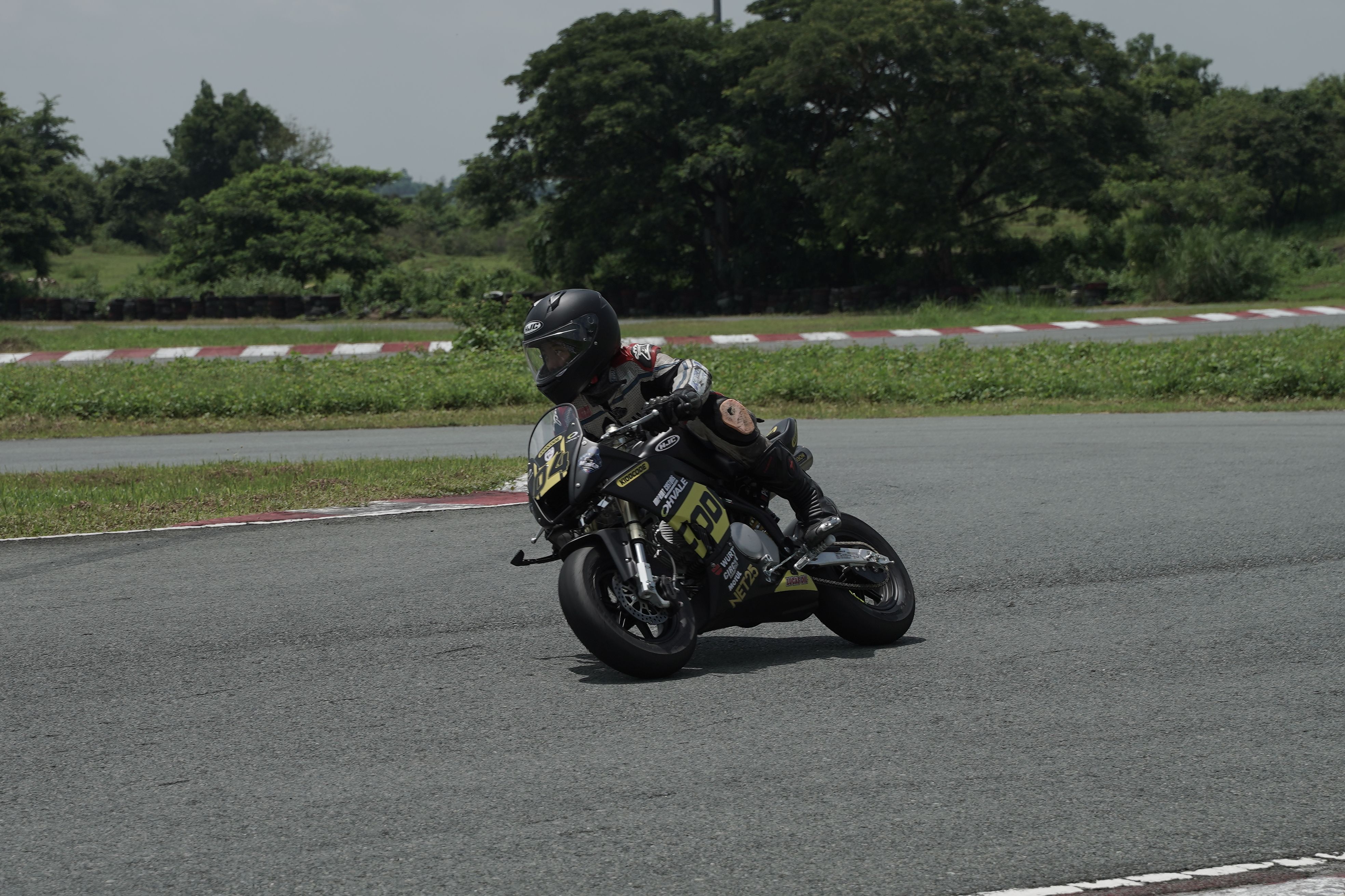 Motorcycle racer cornering on a sunny day at a circuit in Tarlac City, Philippines.