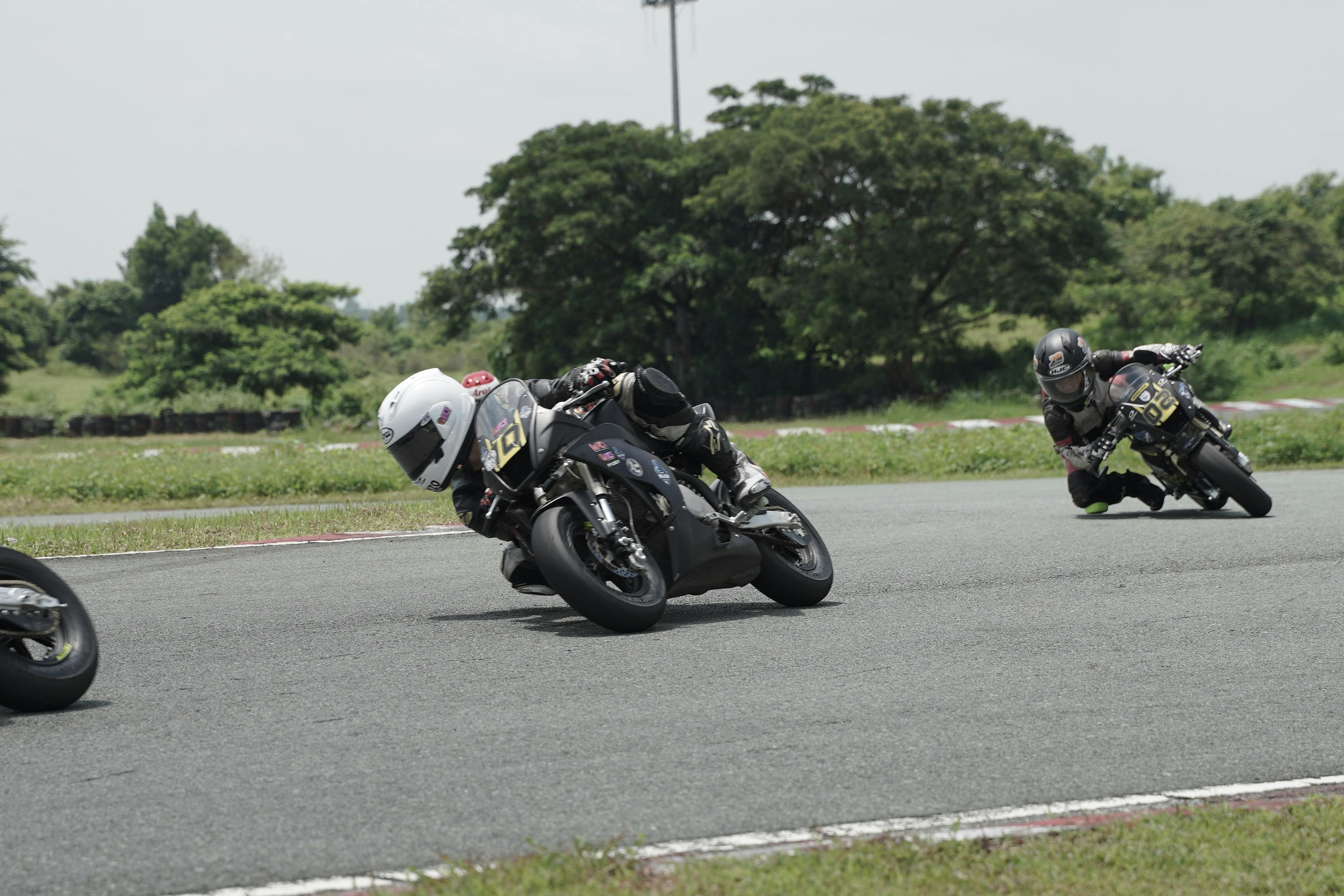 Riders engage in a thrilling motorcycle race on an outdoor circuit, showcasing speed and maneuverability.