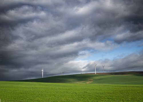Free Wind turbines on a lush green field under dramatic skies, showcasing sustainable energy. Stock Photo