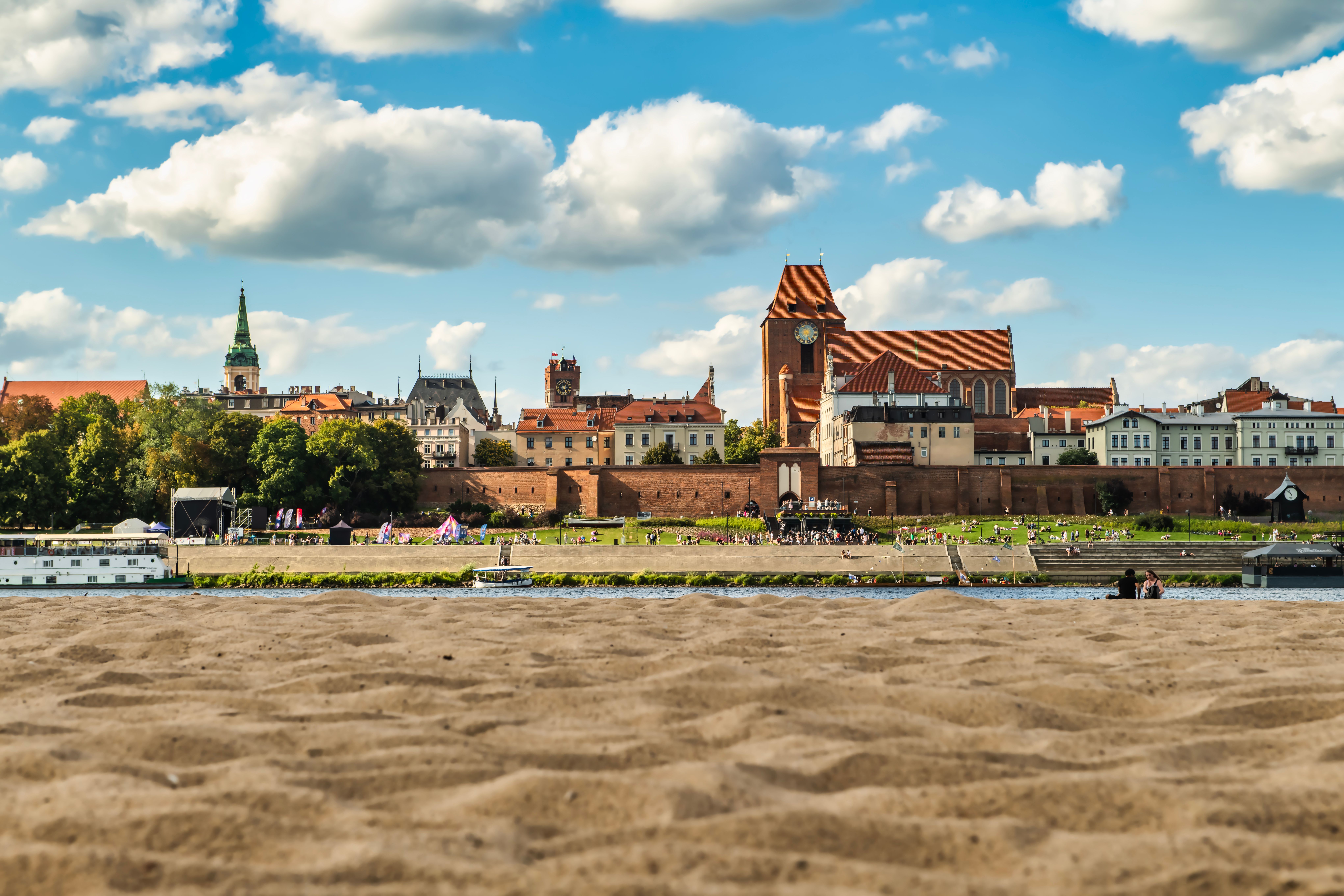 A picturesque view of Toruń's cityscape with architectural landmarks under a vibrant blue sky. — Trójmiasto