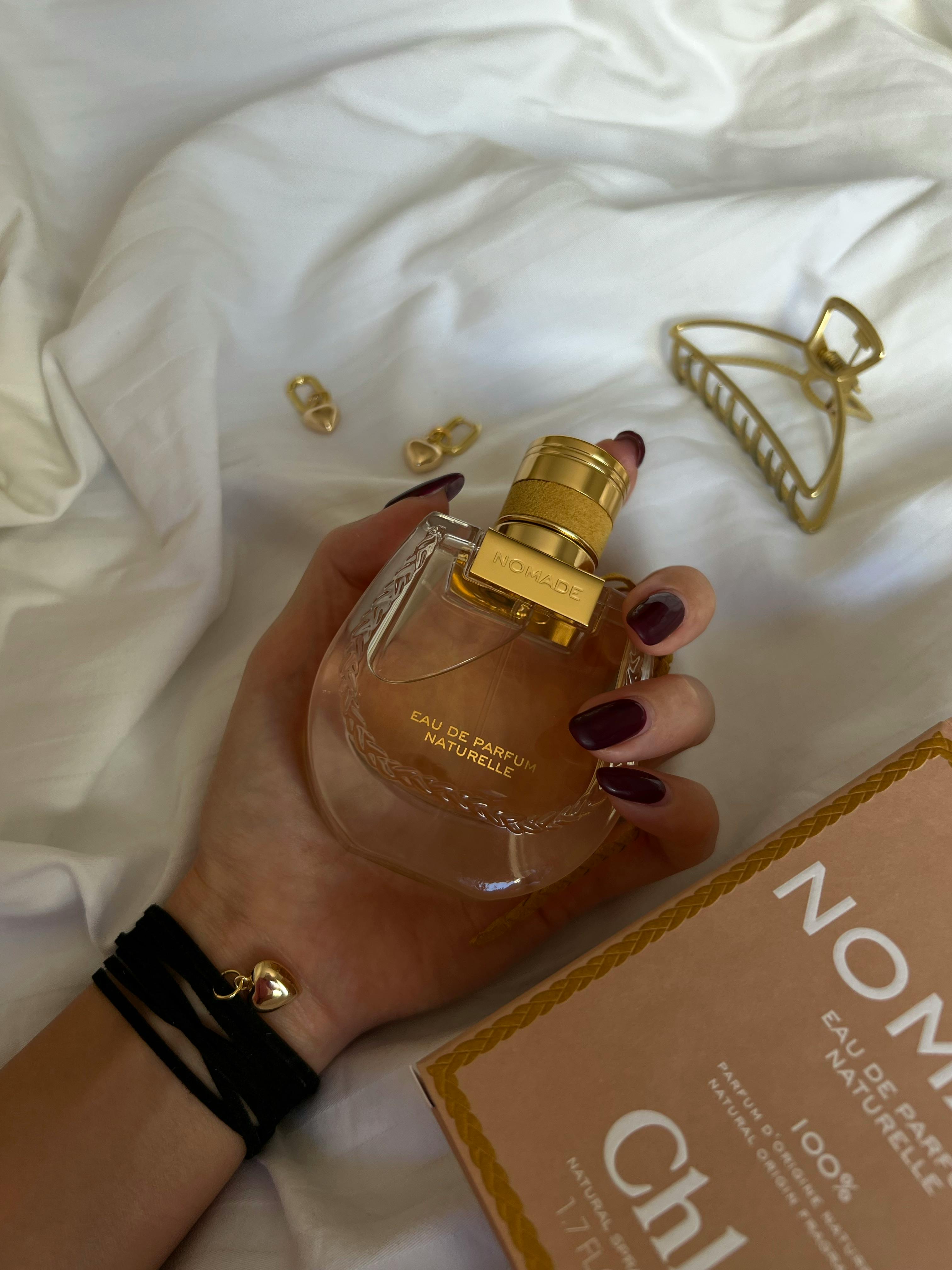 A luxurious perfume bottle elegantly held on soft white sheets.