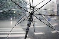 城市街道上，一把透明雨伞的特写，雨滴清晰可见