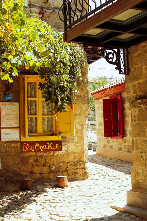 Free Discover the rustic charm of Adatepe with a traditional stone house and colorful windows. Stock Photo