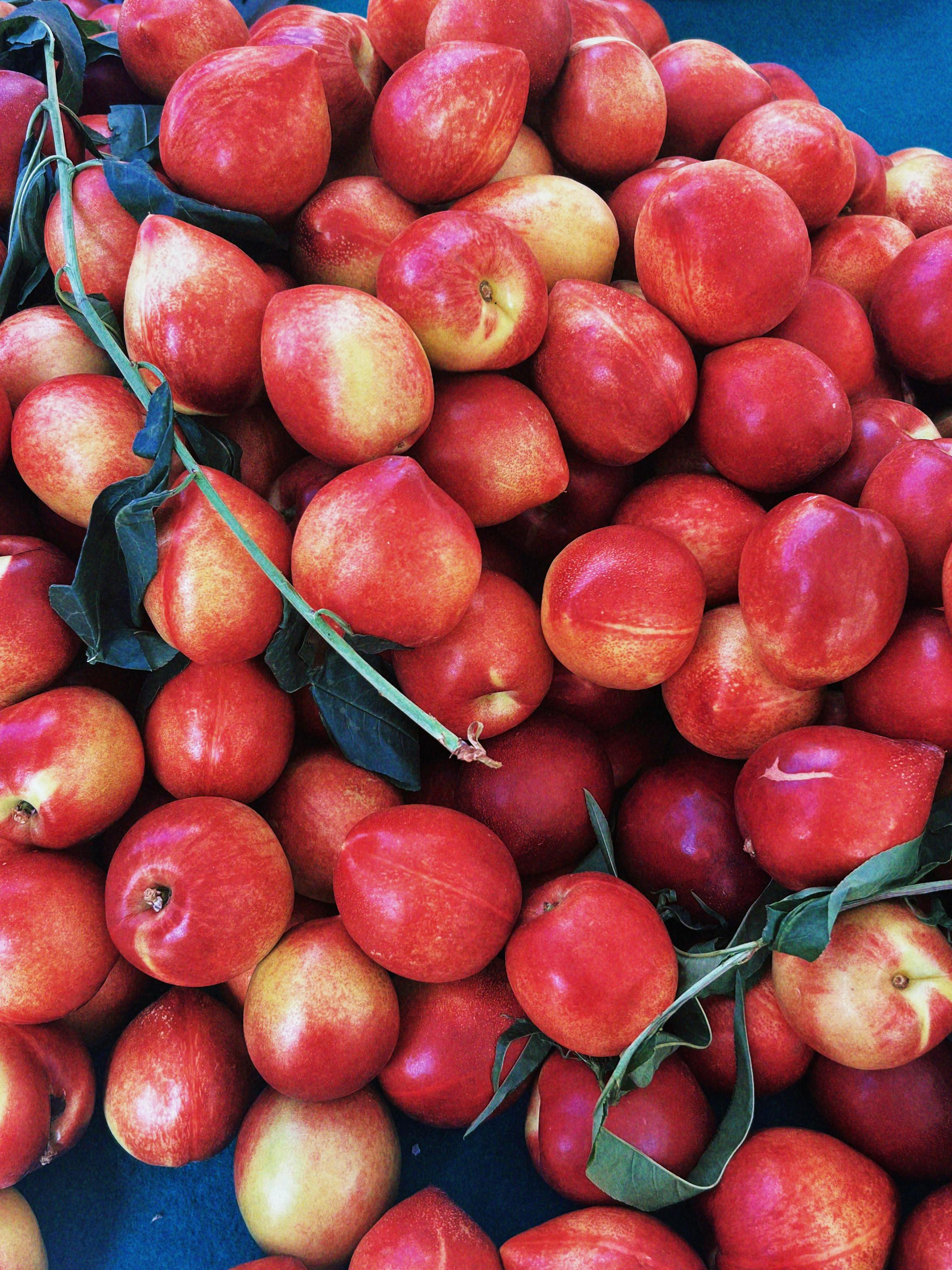 a pile of red apples with leaves on top