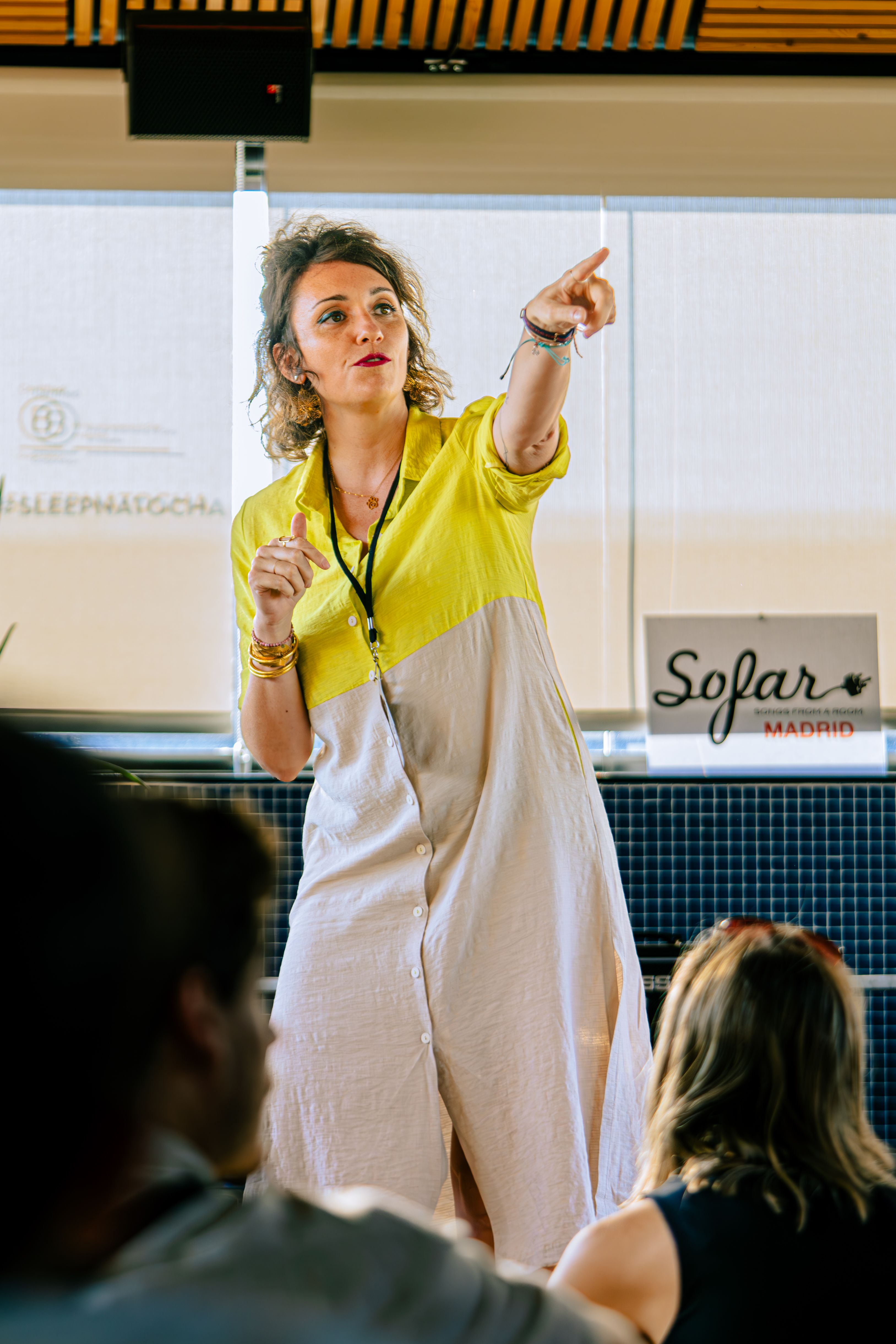 A woman passionately speaking at a Sofar Madrid music event, engaging the audience.