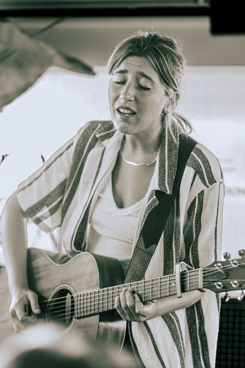 Free Portrait of a woman singing and playing acoustic guitar indoors, exuding a retro feel. Stock Photo