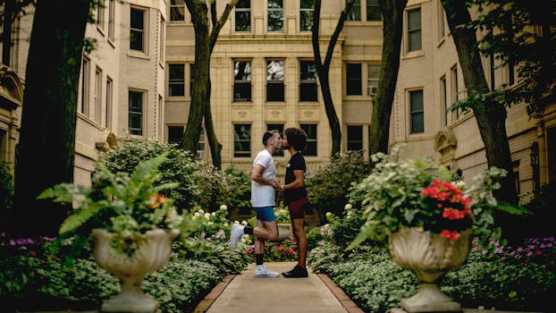A couple shares a romantic kiss in a lush urban garden surrounded by historic buildings in Chicago.