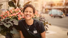 在阳光明媚的日子里，一位快乐的女子在芝加哥市区，被鲜花包围着微笑