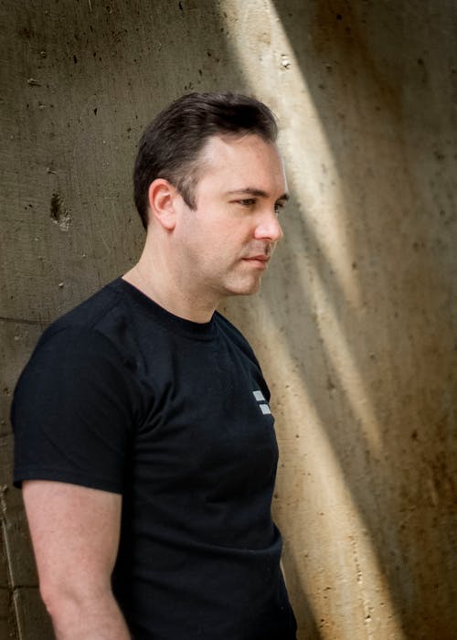 Free Man in Black T-shirt Standing Beside a Wall Stock Photo
