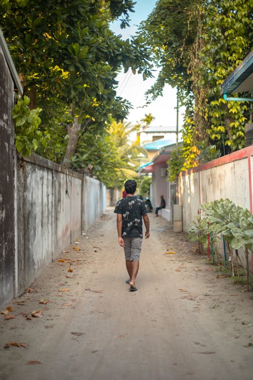 Man Walking on an Alley Between Concrete Fence