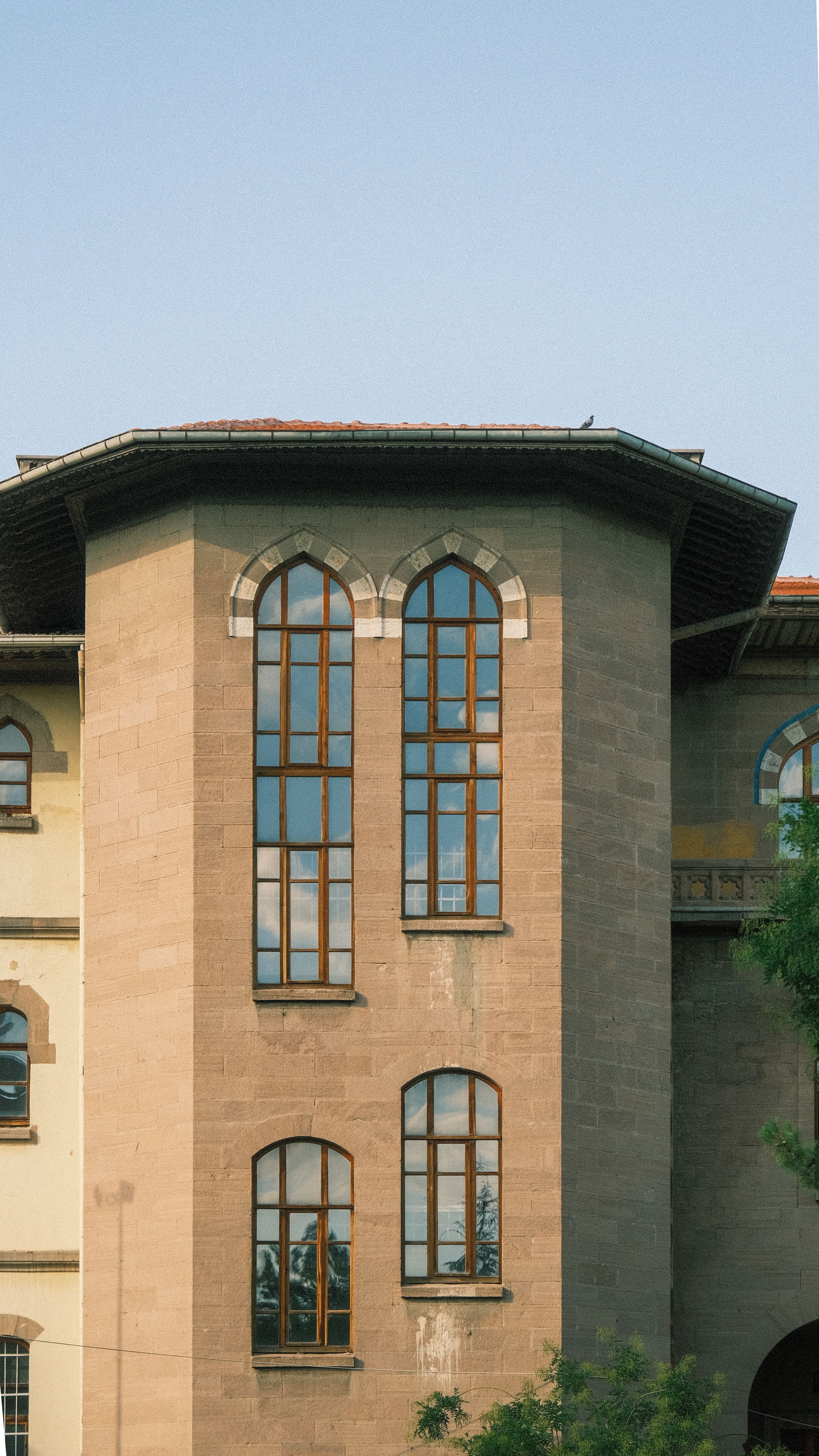 Ancient stone building facade with tall, arched Gothic windows during daylight.