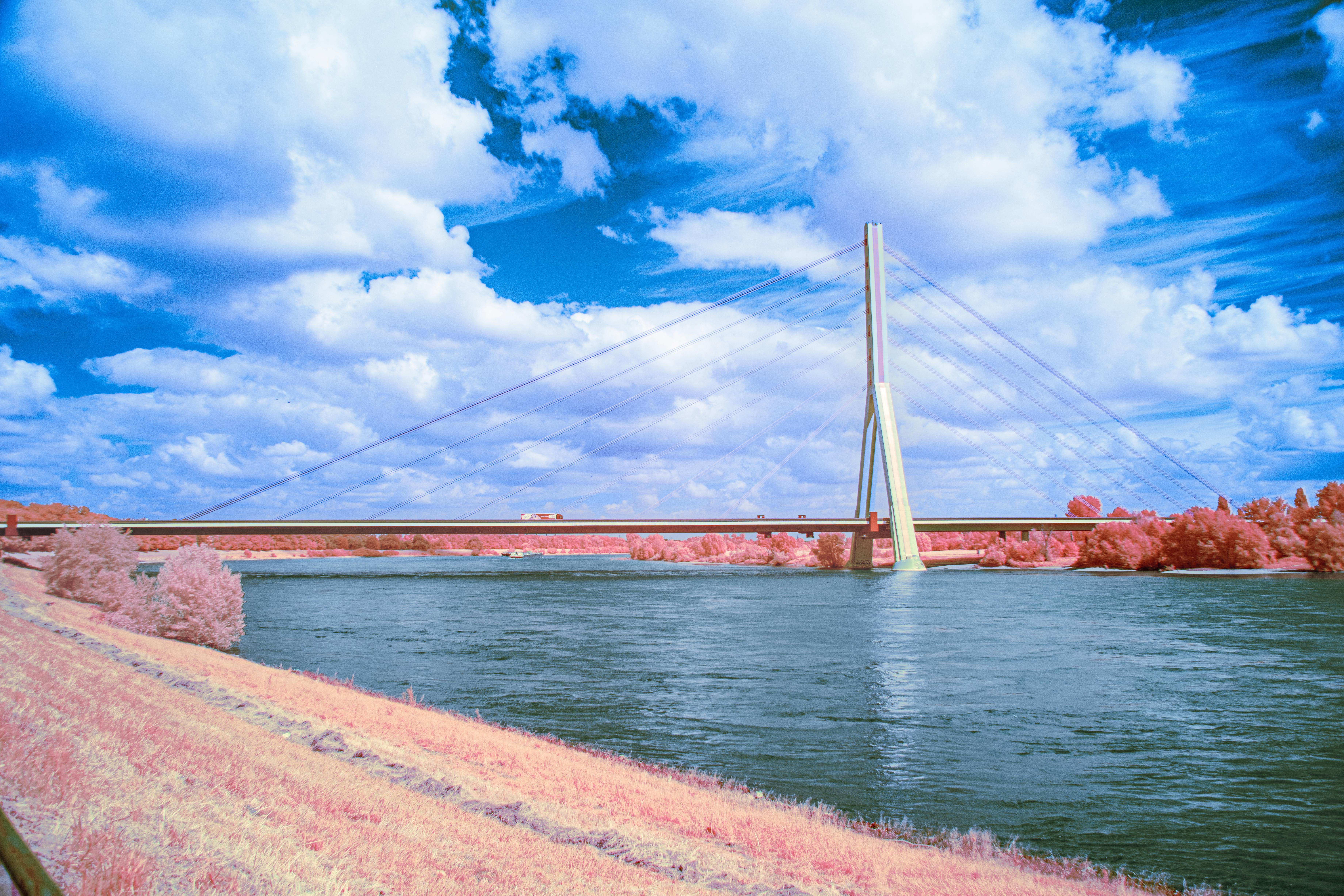 Vivid infrared photo of a bridge over a river under a bright blue sky.