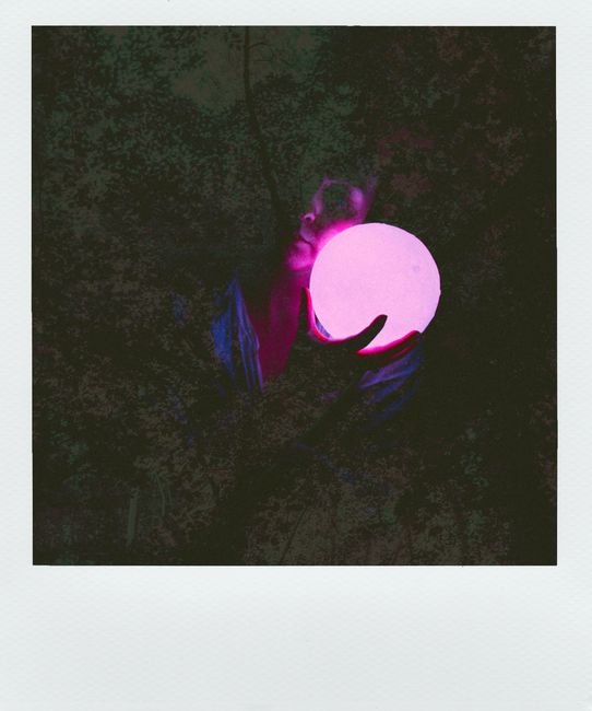 A captivating photo of a person holding an illuminated orb in a dark, artistic setting.