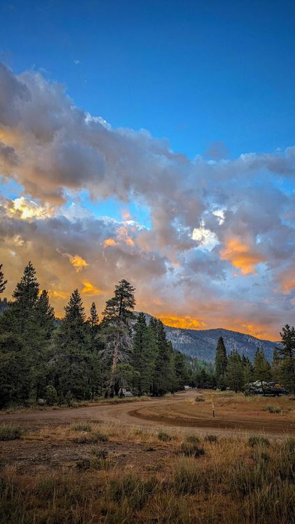 A sunset over a mountain range and trees · Free Stock Photo
