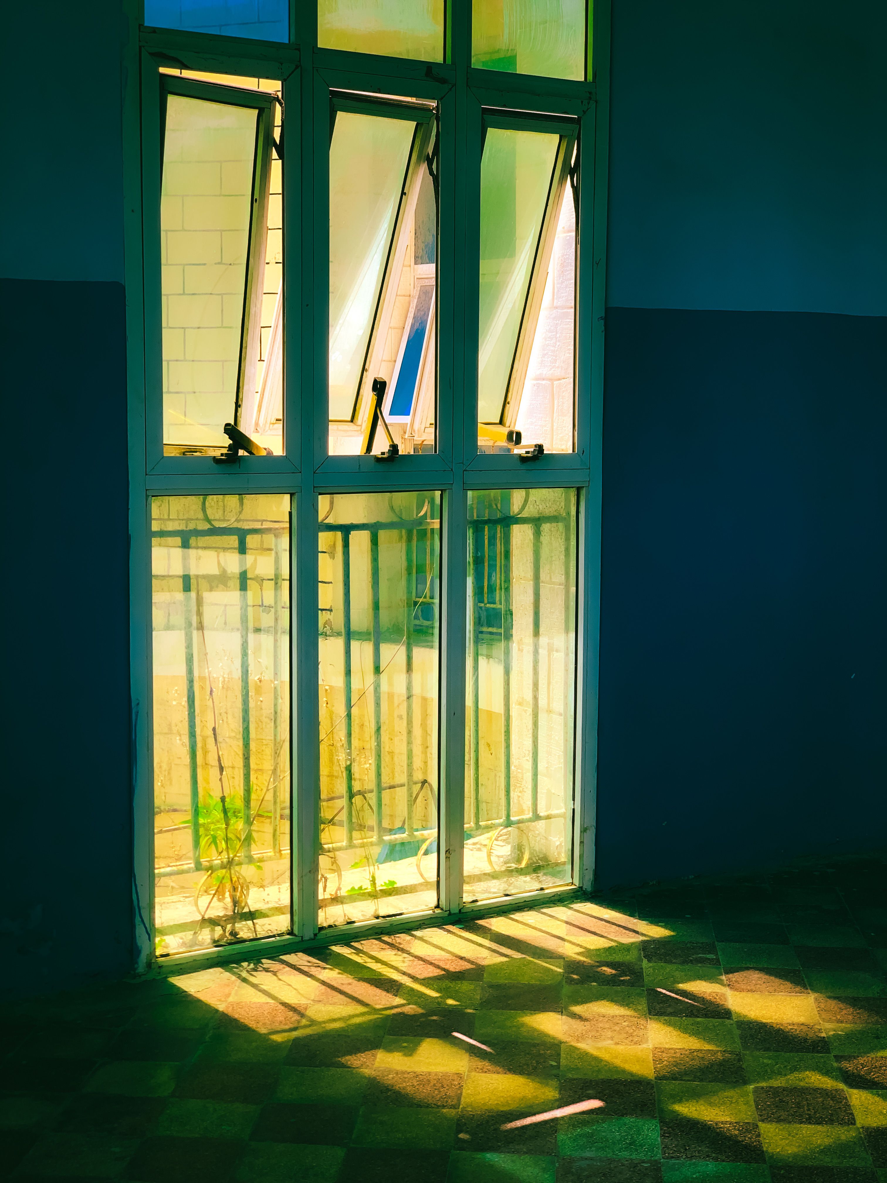 A wide shot of a room with sunlight streaming through a toilet paper roll kaleidoscope window, casting colorful geometric patterns on the walls and floor.