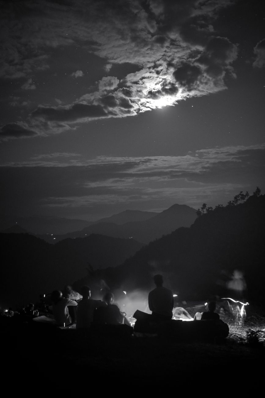 group gathered around a roaring campfire under a starry sky