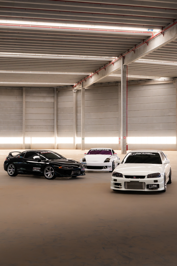 Três carros esportivos de alto desempenho estacionados em uma garagem interna moderna e elegante.