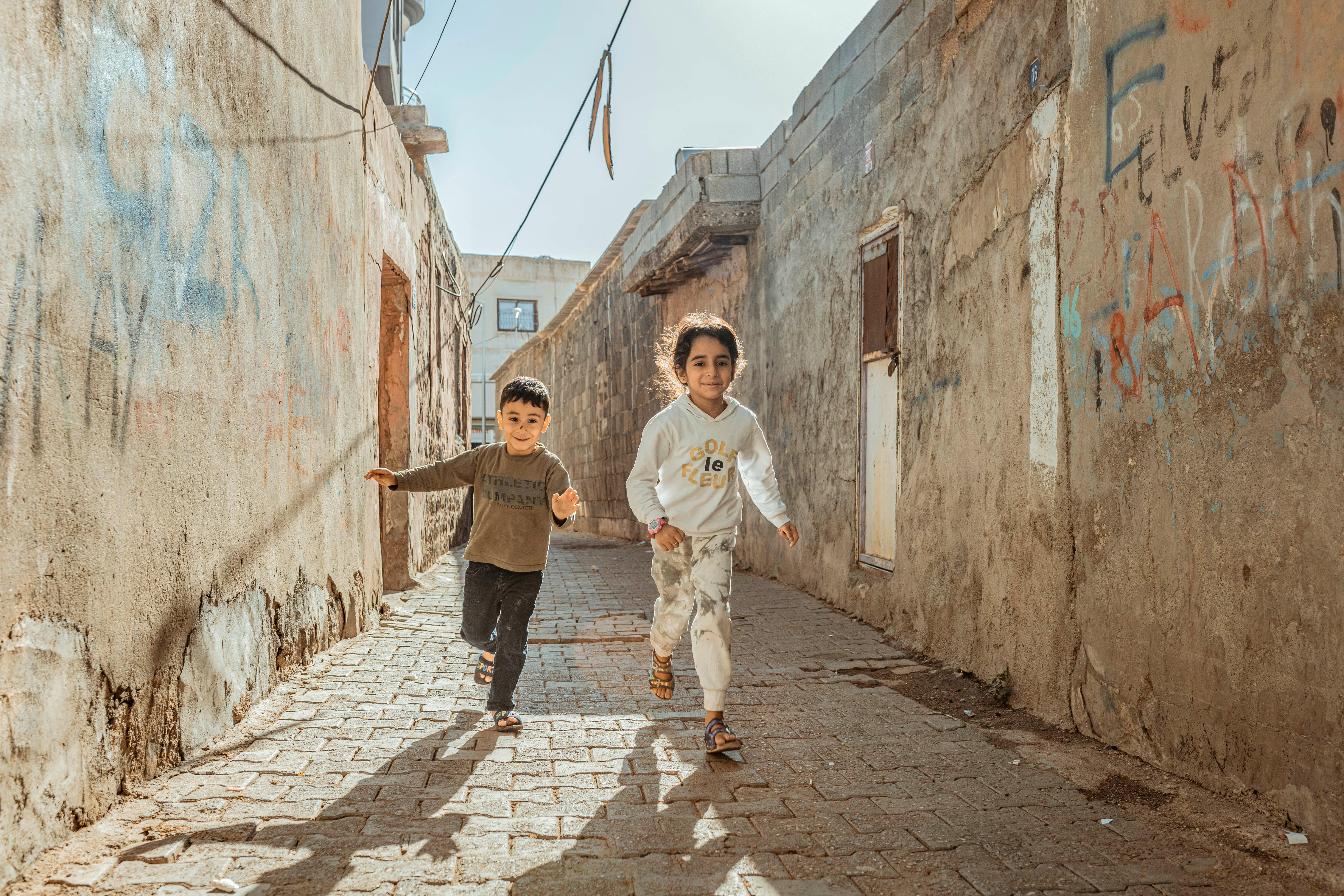 children running through street past abandoned building