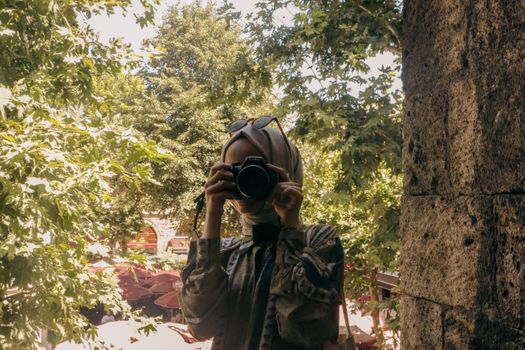A woman with a camera captures a scenic outdoor park view in summer.