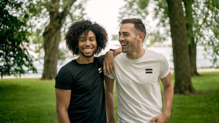 Two Men Standing On Grass Field